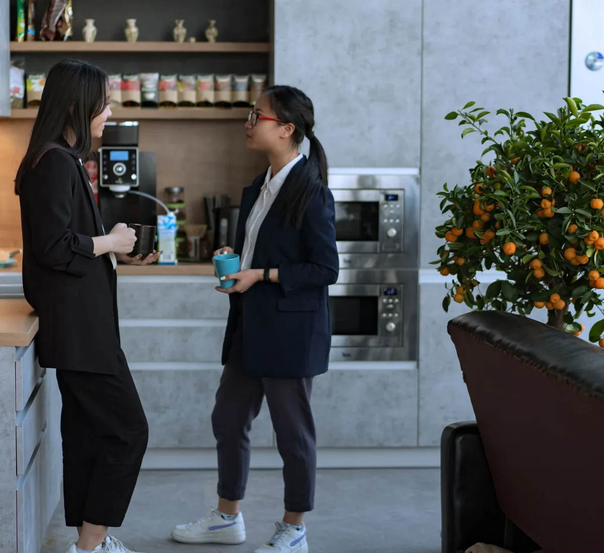 Two colleagues talking over coffee in an office kitchen